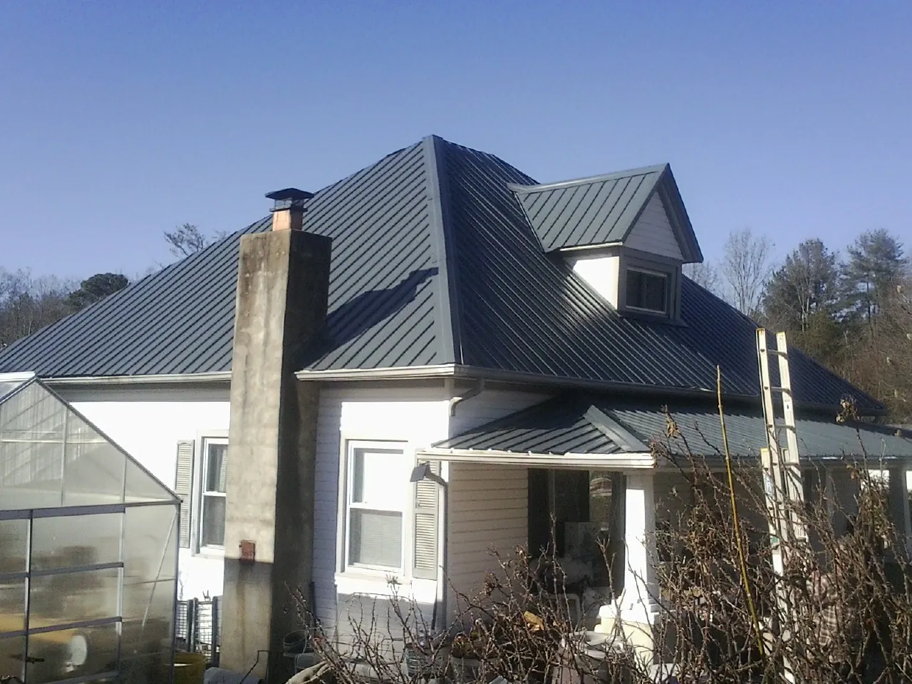 Dark blue standing seam metal roof on a white farmhouse with dormer — Slate & Tile Roof Repair by Roofing Brothers in Paige