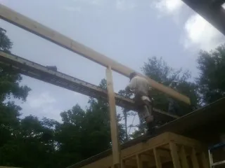 Carpenter setting a ridge beam over a new addition frame — Ice Dam Removal by Roofing Brothers in Paige