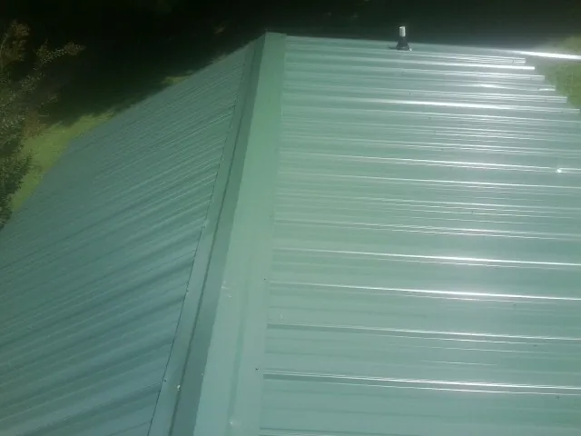 New green metal panels meeting at the ridge of a roof — Flat Roof Repair work by our crew in Paige