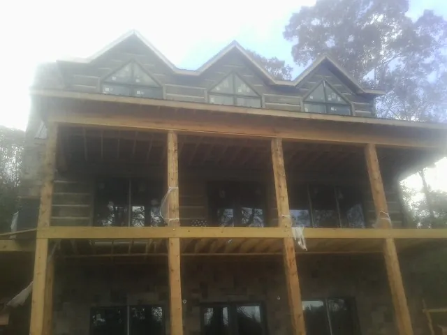 Dormers and porch framing on a large log home under construction — Roof Coating work by our crew in Paige