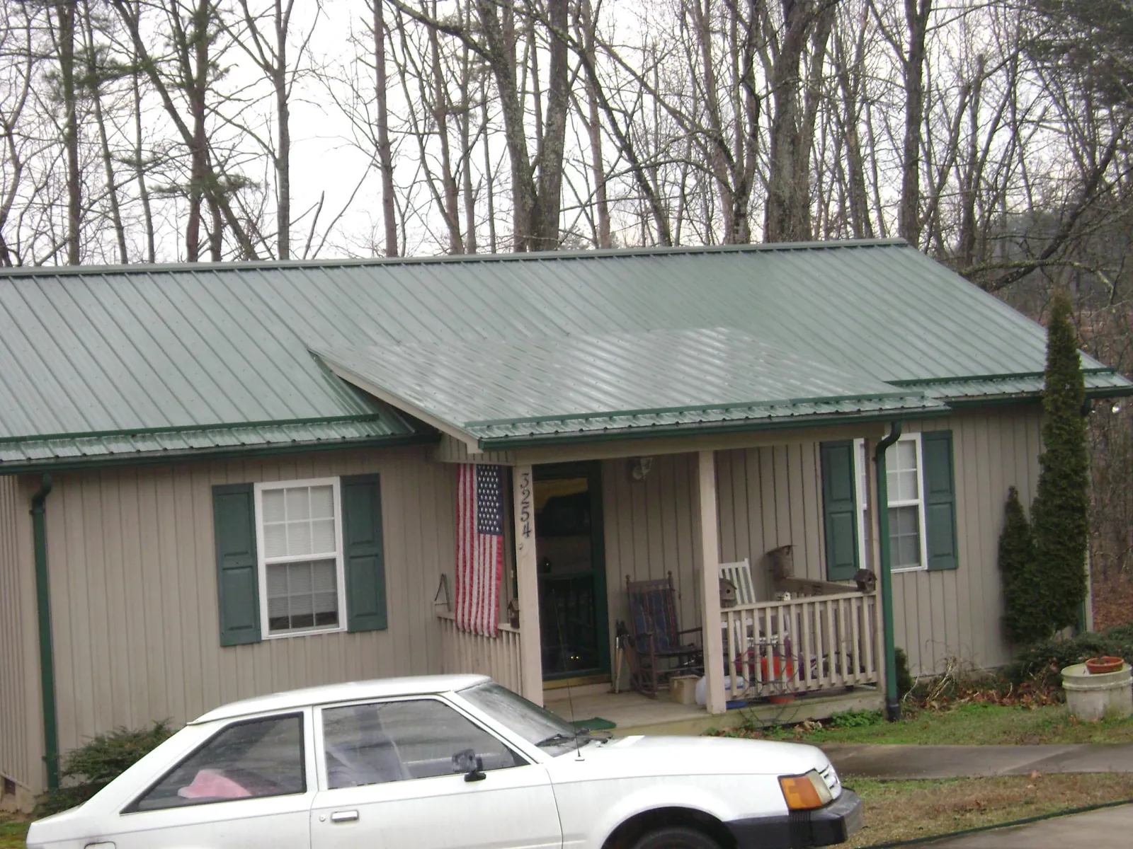 Green metal roof and front porch on a tan sided cottage in Paige