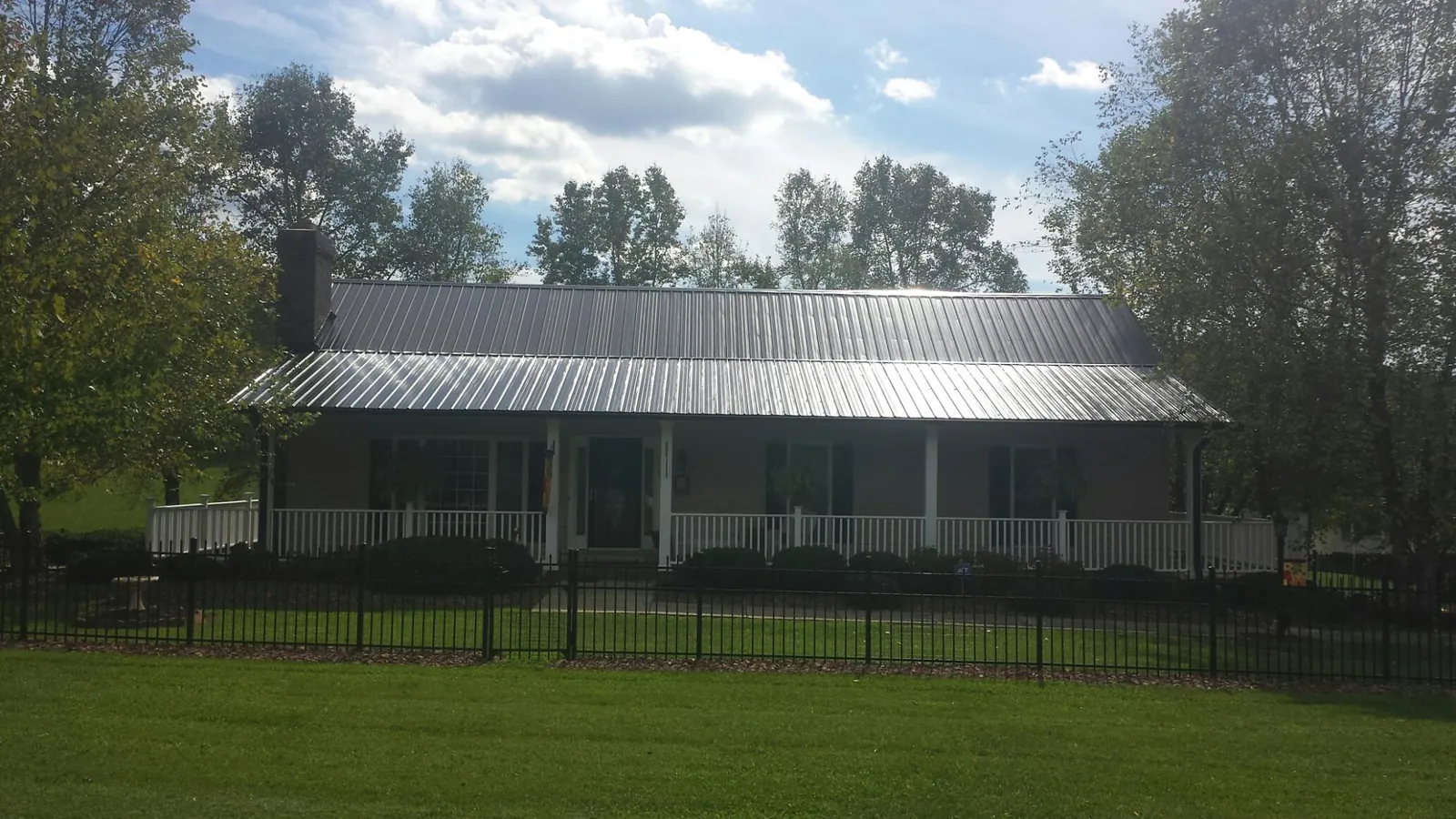 Gray metal roof on a brick ranch with a full width front porch — Gutter Guard Installation work by our crew in Paige