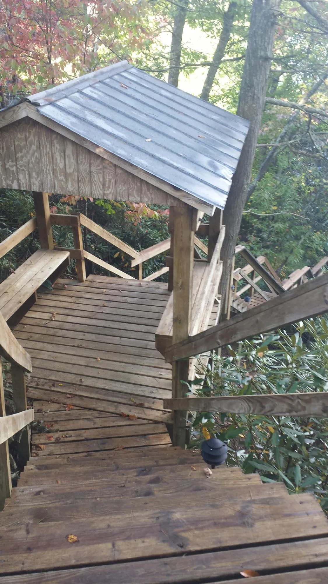 Metal roofed shelter over wooden steps on a wooded walkway — Skylight Repair & Installation work by our crew in Paige