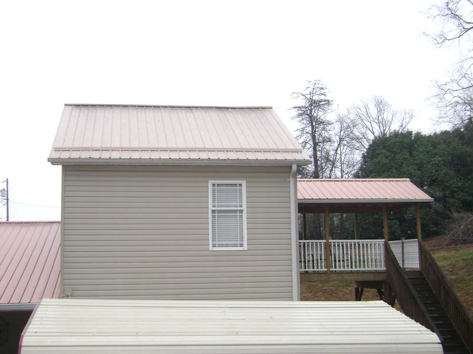 Tan metal roofs on a two story addition and attached porch, from a Roof Replacement job in Paige