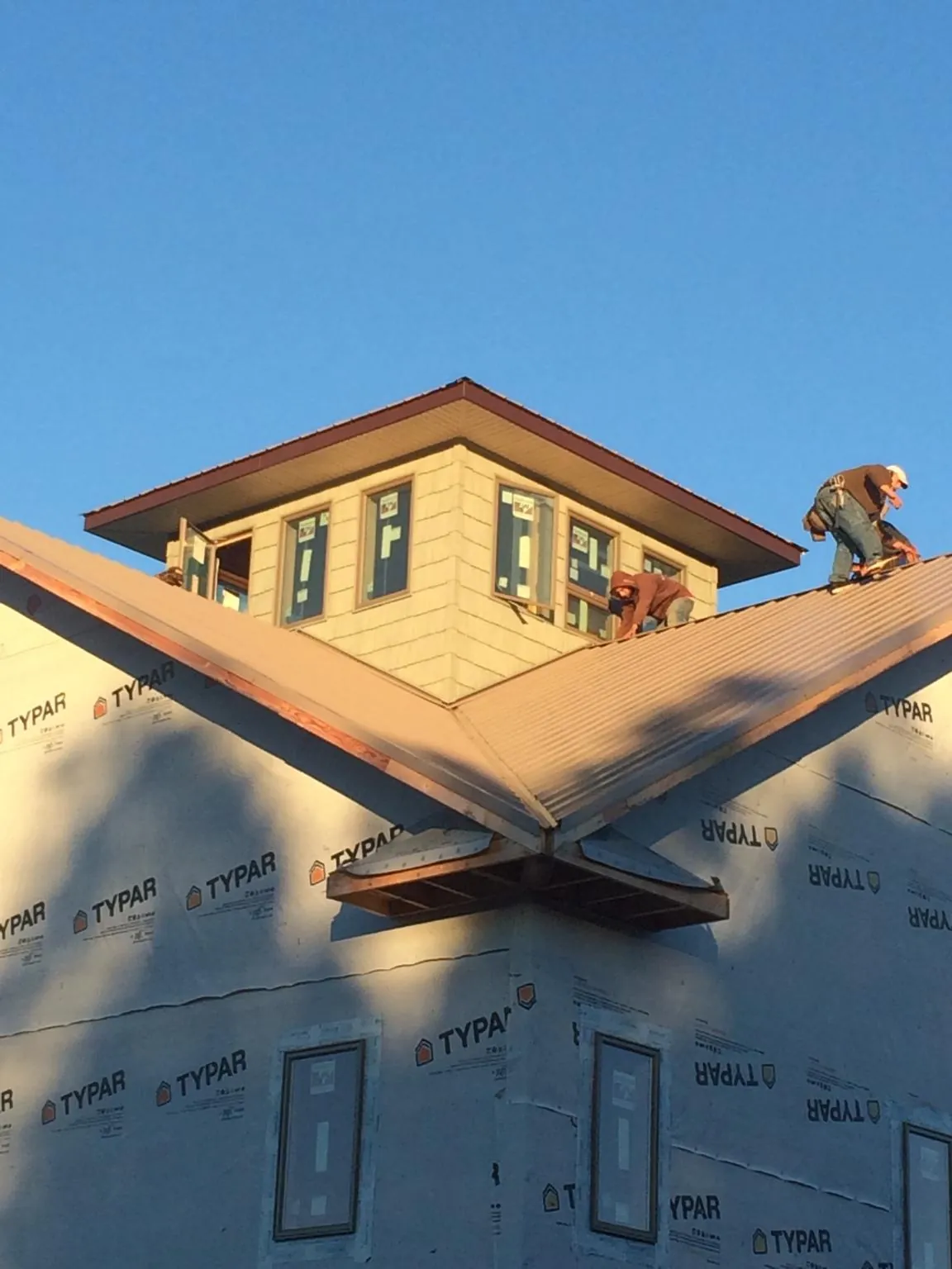 Roofers working around a rooftop cupola on a new metal roof at sunset — Roof Waterproofing in Paige by Roofing Brothers